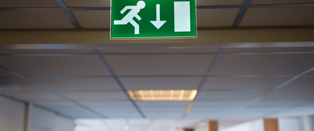 Emergency exit sign hanging from a ceiling