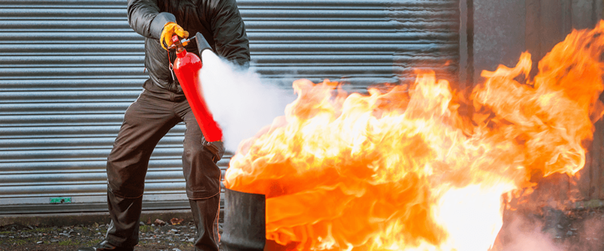 A man putting out a fire using a fire extuinguisher